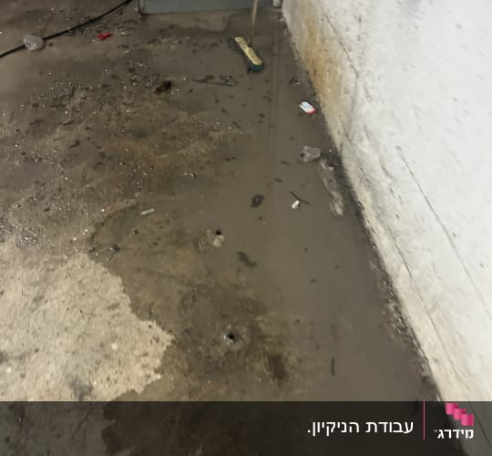 רצפה מלוכלכת עם מים ומטאטא בפינה